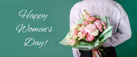 Man holding and giving a beautiful bouquet with flowers to woman on green background. Front view. Womens day, love concept. Copy space. Bannerの写真素材