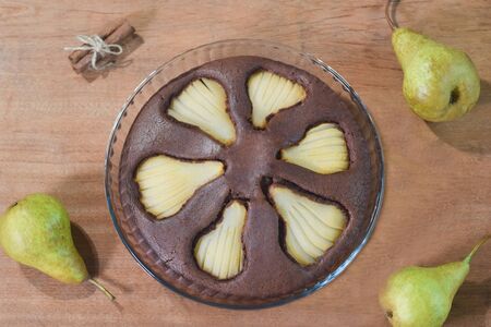 Chocolate cake with pears and cinnamon on wooden backgroundの写真素材