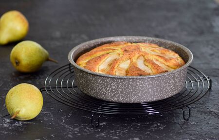 Freshly baked pear cake in a baking dish on a black backgroundの写真素材