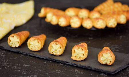 French cream horn. Puff rolls with cream on a dark background