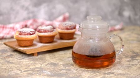 Kettle with tea and roses buns, sweet buns with sugar powder.の写真素材