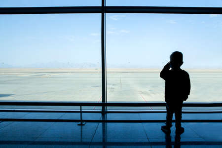 Boy looking through a window at the empty airport.の写真素材