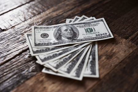 Amount of dollars are lying on the wooden brown table. Dollars are located in fan position.の写真素材