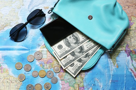 Some staff for travel. Money, glasses, bag, phone, coins are located on the intrenational map.の写真素材