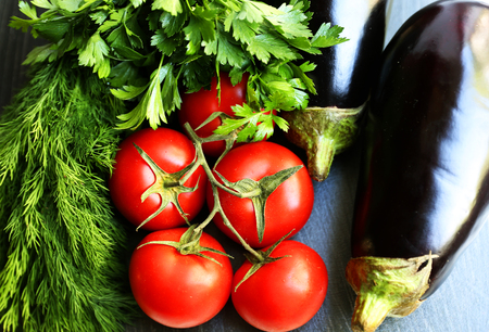 Tasty seasonal vegatables: eggplants, tomatos, garlic, parsley are on the tableの写真素材