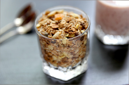 Granola is for the breakfast in the transparent glass with yogurt, napkins and spoons on the grey backgroundの写真素材