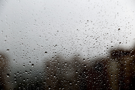 Rain drops on the window with the reflection of the city on the backgroundの写真素材
