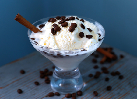 White ice-cream is with sinabon and coffee on the blue table in rustic style.の写真素材