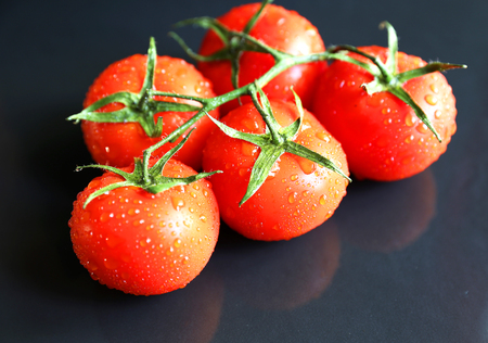 Bunch of red fresh tomatoes on black stone backgroundの写真素材