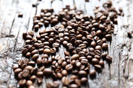 Coffee beans are on the wooden textured table with the glass jarの写真素材