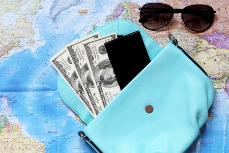 Some staff for travel. Money, glasses, bag, phone, coins are located on the intrenational map.の写真素材