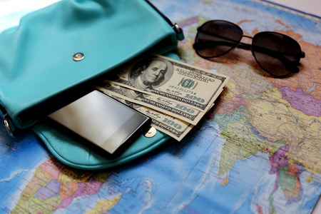Some staff for travel. Money, glasses, bag, phone, coins are located on the intrenational map.の写真素材