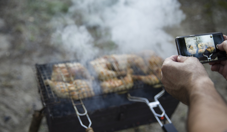 Barbecue in the outdoor. Man is doing photo