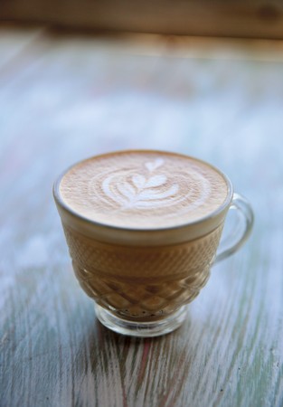 Cup of cappuccino is on the wooden texture tableの写真素材