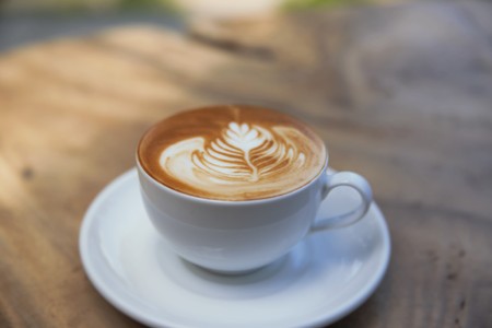 Cup of cappuccino is on the wooden texture tableの写真素材