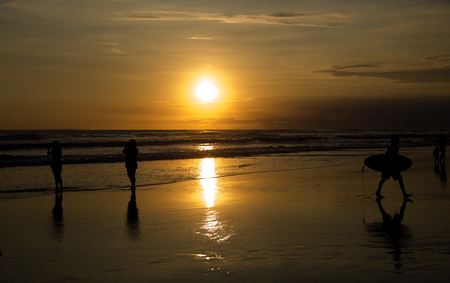 People's silhouettes are on the ocean beach on the sunsetの写真素材