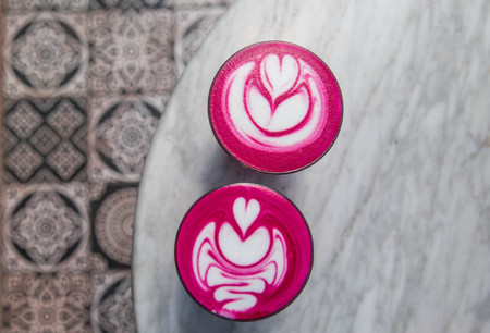 Two colorful trendy pink beetroot latte on white marbel background.の写真素材