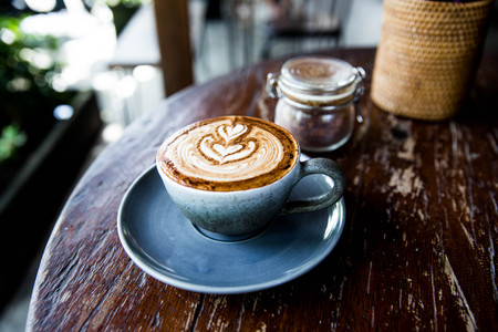 Cup of hot latte coffee on wooden tableの写真素材