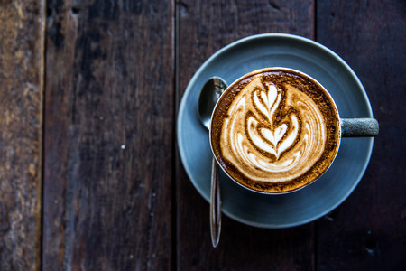 Cup of hot latte coffee on wooden tableの写真素材