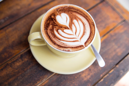 Cup of hot latte coffee on wooden tableの写真素材