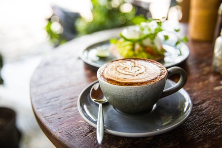 Cup of hot cappucino on the wooden textured vintage table. It is an art on latteの写真素材