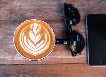 Cup of hot cappucino is on wooden table background. hippster styleの写真素材