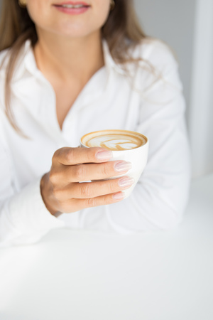 Woman is holding cup of cappuccino coffeeの写真素材