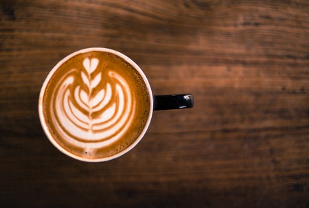 Cup of hot cappucino is standing on the wooden table.の写真素材