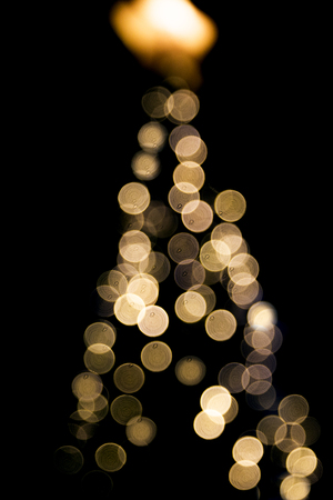 Blurred abstract golden sparkling lights on Christmas tree background on black backdrop. Festive concept. Place for design.の写真素材