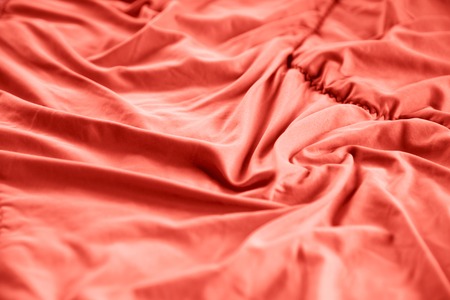 Close up of bedding sheets with coral color on morning bed.の写真素材