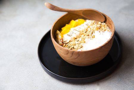 Mango smoothie bowl with strawberry and coconut and oatmeal on the table. Healthy food. Close upの写真素材
