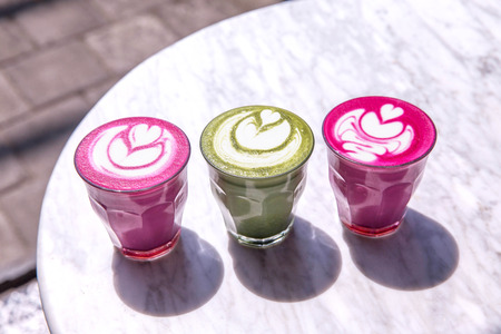 Three colorful Beetroot, matcha lattes on marble table background.の写真素材