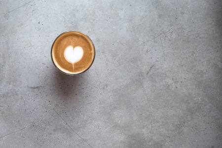 Glass of tasty latte with love art on concrete textured background.の写真素材