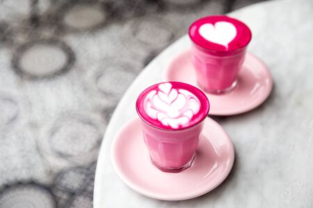 Two glasses of pink beetroot latte with beautiful latte art on marble table background. Trendy healthy drink.の写真素材