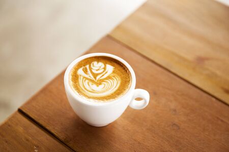One cup of cappuccino with beautiful latte art on wooden brown background.の写真素材