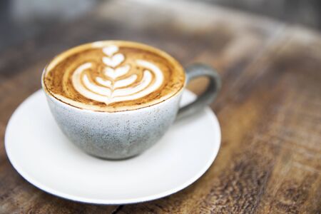 One cup of cappuccino with beautiful latte art on wooden brown background.の写真素材