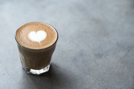 Glass of tasty latte with love art on concrete textured background.の写真素材