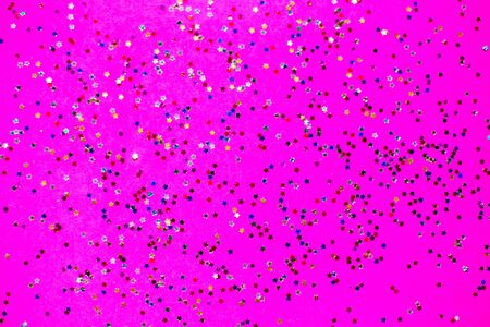 Multicolored stars glitter on brigth pink neon background. Festive holiday backdrop.の写真素材