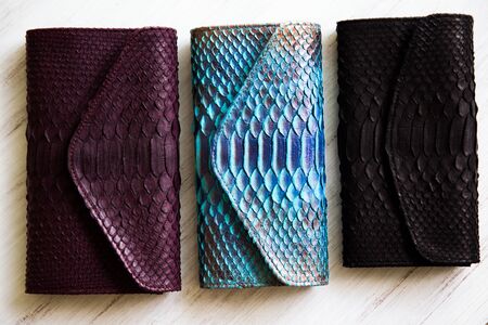 Three different colorful wallet from trendy painted snake python skin. Top view. Fashion concept.