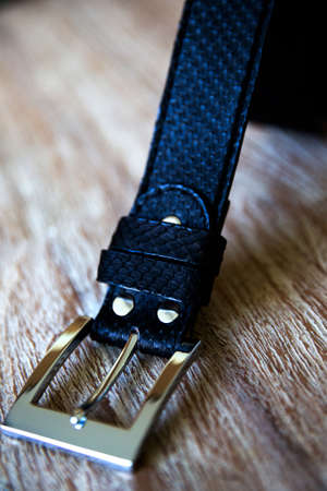 Close up of black leather belt on a wooden surface. Fashion men set.