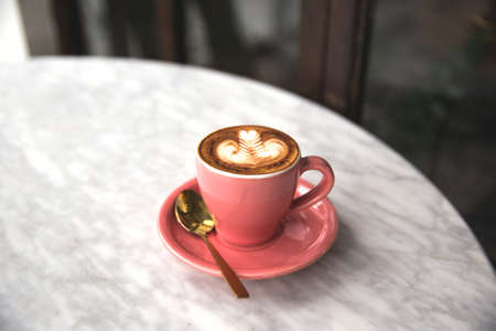 Pink cup of hot cappuccino on white marble table.の写真素材