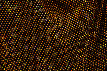 Golden sparkling background of festive material with wavy folds.
