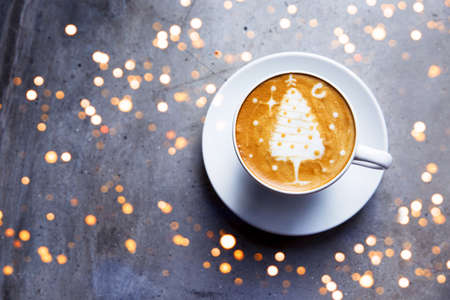 Tasty cappuccino with Christmas snowman art with some blurred lights.の写真素材