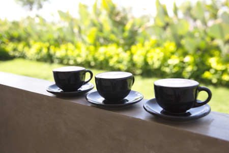Three Cups of hot cappuccino on concrete bar table with green sunny background. Morning tropical conceptの写真素材