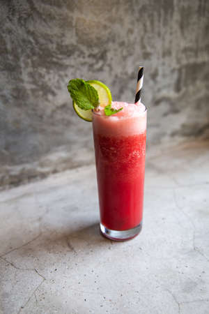 Glass of watermelon smoothie with lime and mint on concrete background.の写真素材