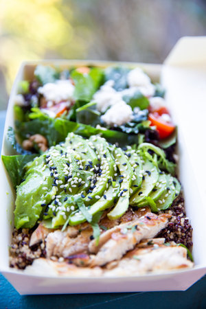 Healthy chicken salad with avocado in disposable white paper package