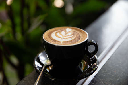 Cup of tasty cappuccino with latte art on wooden table background.の写真素材