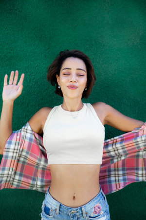 Confident emotional middle easten young woman standingby green wall background.の写真素材
