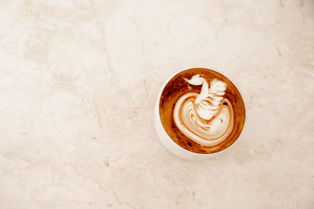 White cup of tasty cappuccino with latte art on white marble background in cafe, Loft interior. top viewの写真素材