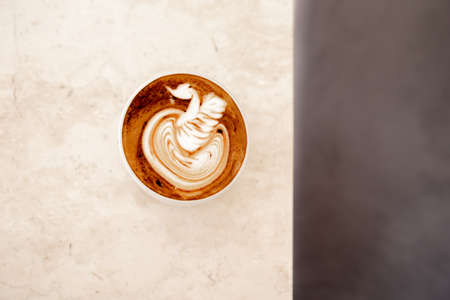 White cup of tasty cappuccino with latte art on white marble background in cafe, Loft interior,の写真素材